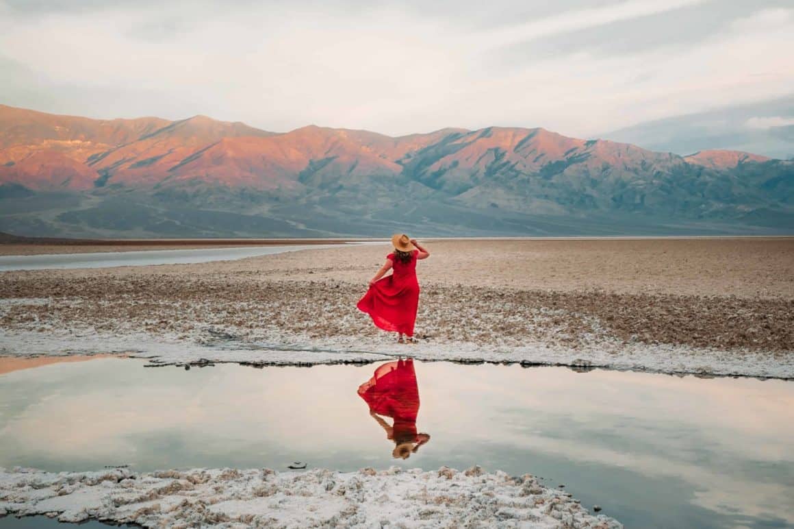 Woman in orange dress near lake and mountains
