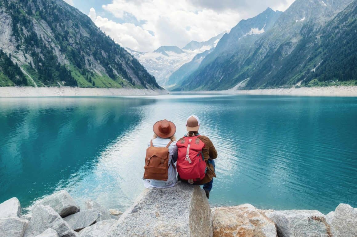 Couple sitting on rock looking at lake while travelling