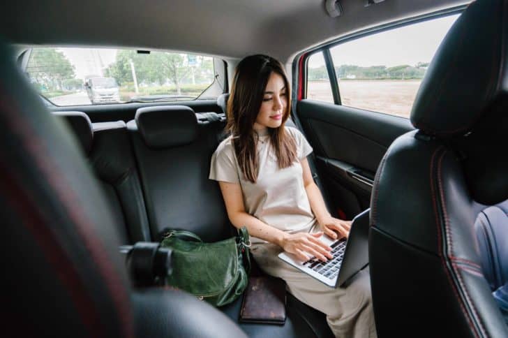 Woman travelling in car on laptop.