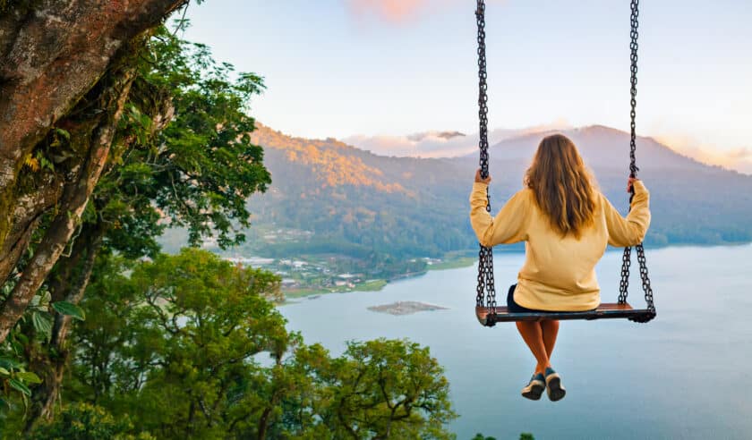 Image of girl on a swing overlooking mountains and the ocean